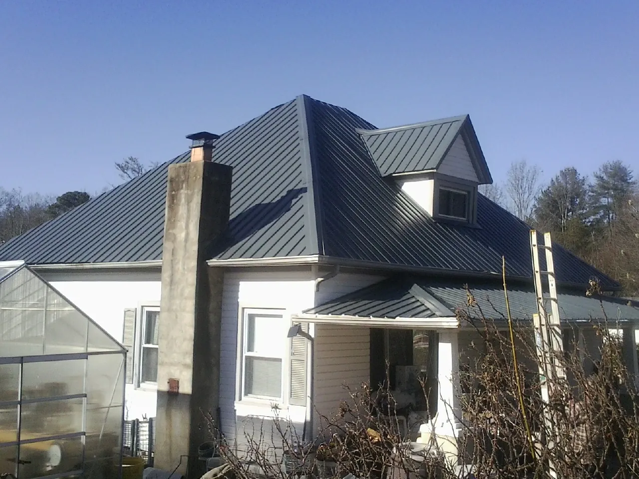 Dark blue standing seam metal roof on a white farmhouse with dormer — Slate & Tile Roof Repair by Roofing Brothers in Harveys Lake