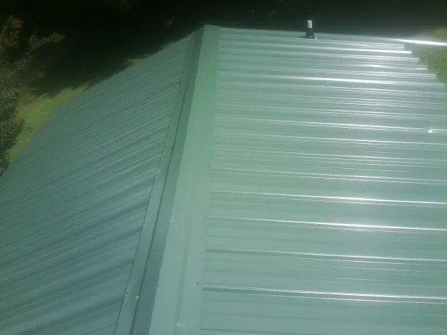 New green metal panels meeting at the ridge of a roof — Flat Roof Repair work by our crew in Harveys Lake