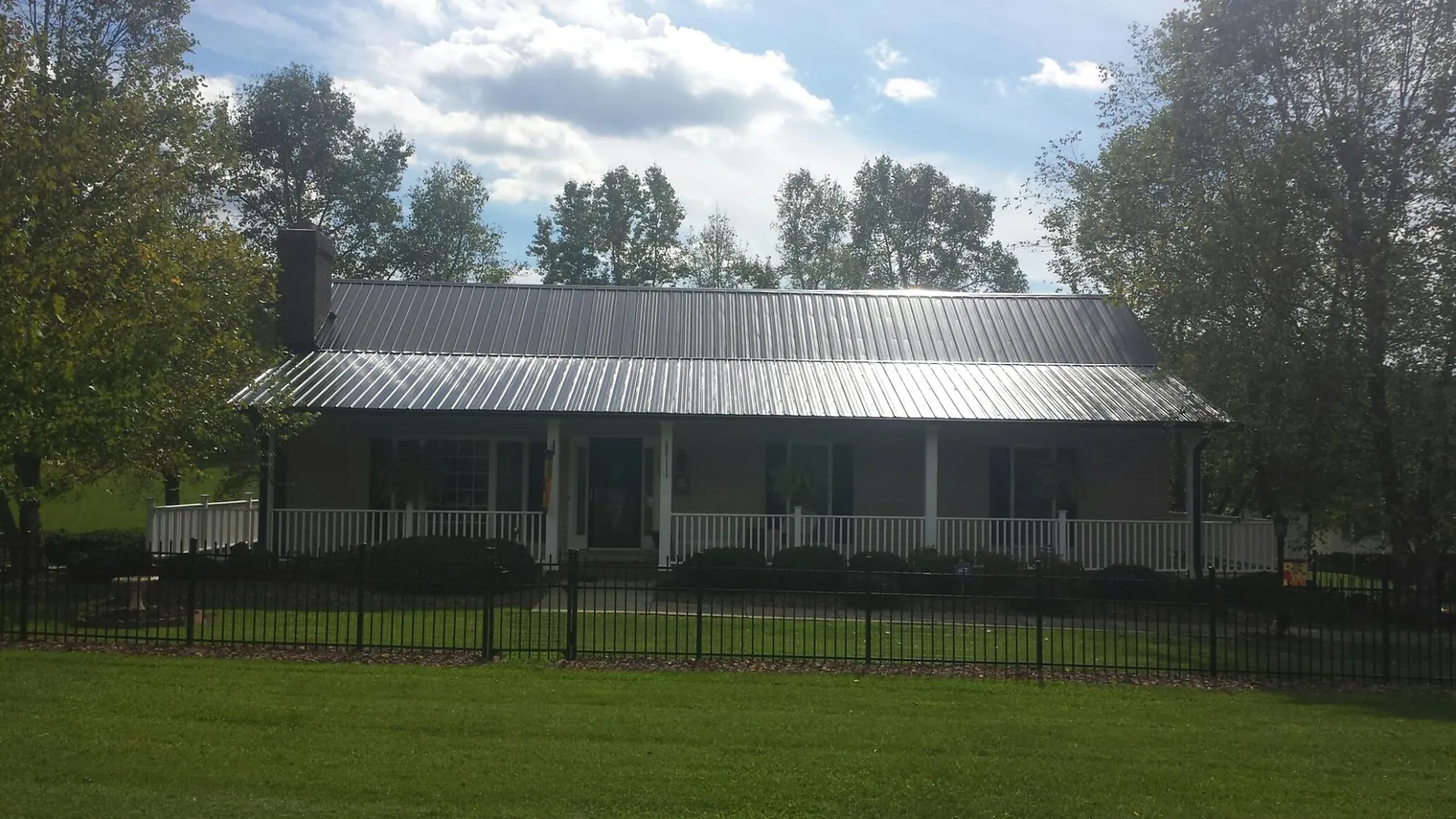 Gray metal roof on a brick ranch with a full width front porch — Gutter Guard Installation work by our crew in Harveys Lake