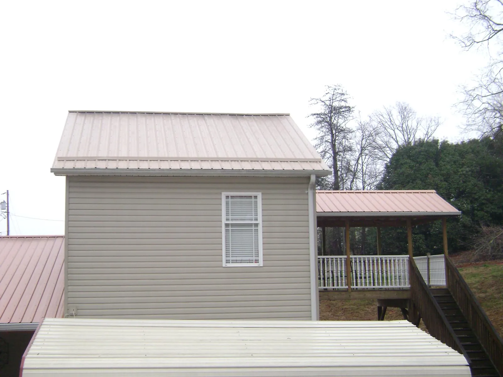 Tan metal roofs on a two story addition and attached porch, from a Roof Replacement job in Harveys Lake