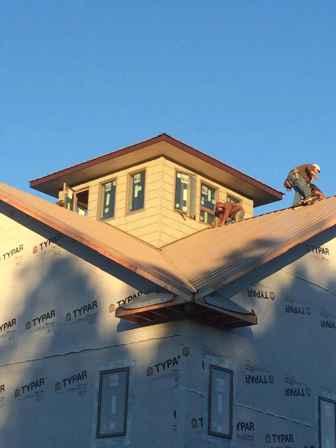Roofers working around a rooftop cupola on a new metal roof at sunset — Roof Waterproofing in Harveys Lake by Roofing Brothers